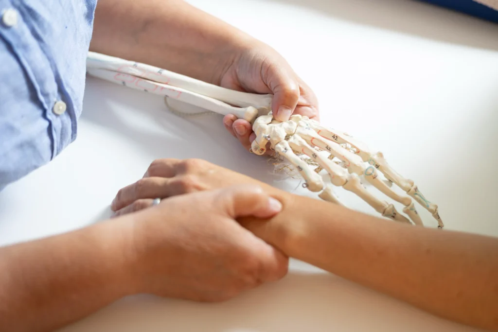 Ergotherapeutin zeigt Patienten etwas mit einer Skelett Hand